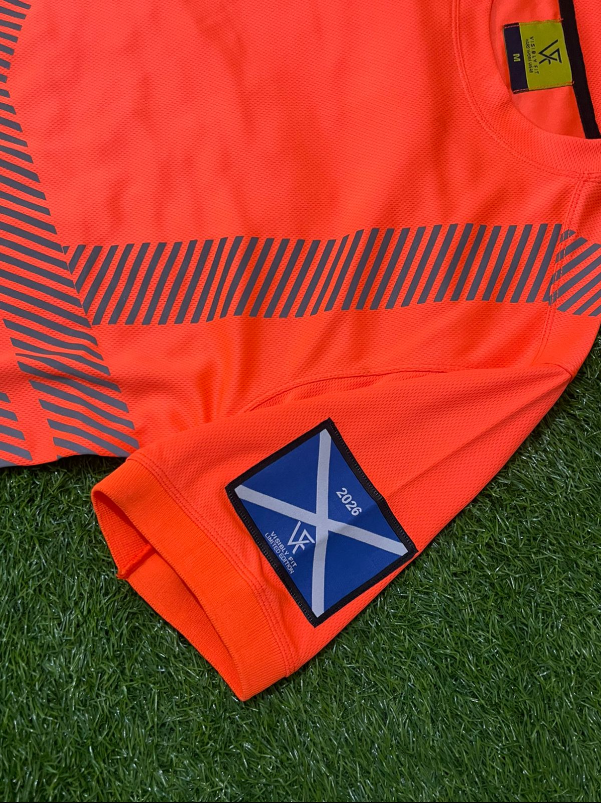 Orange sports jersey with a blue and white logo on grass
